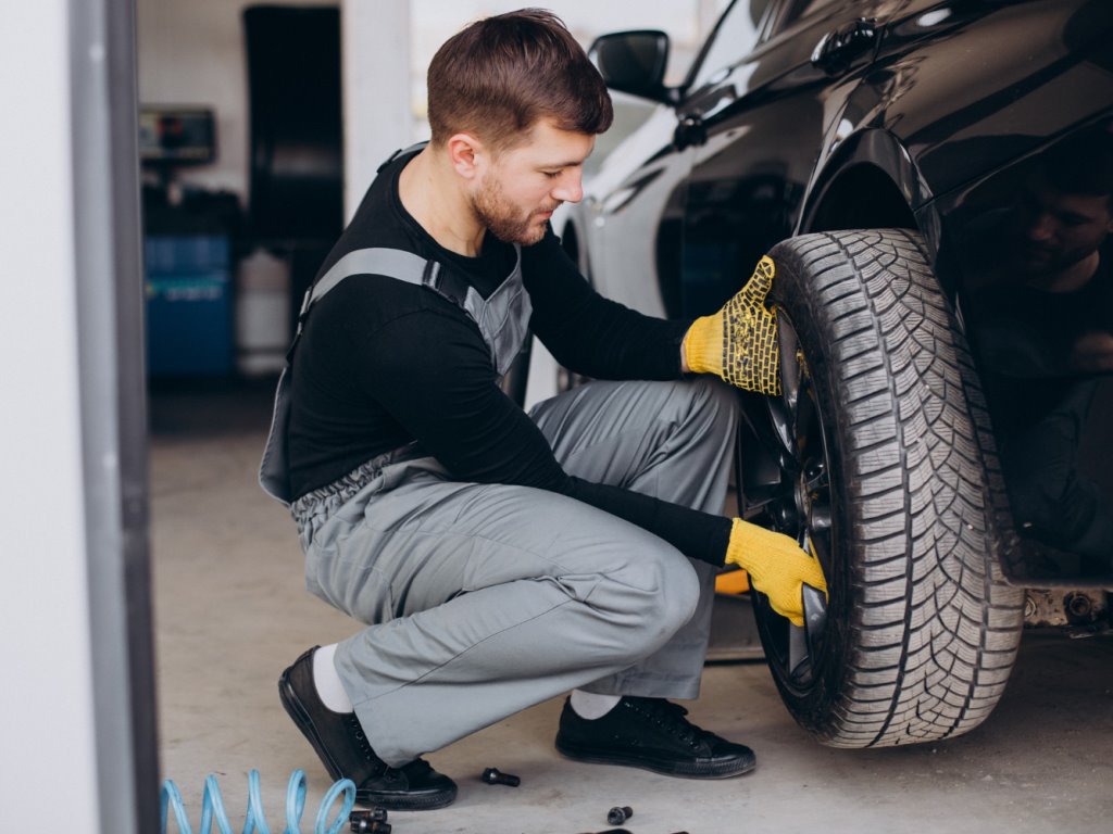 mecánico joven realiza mantenimiento de neumáticos en un taller