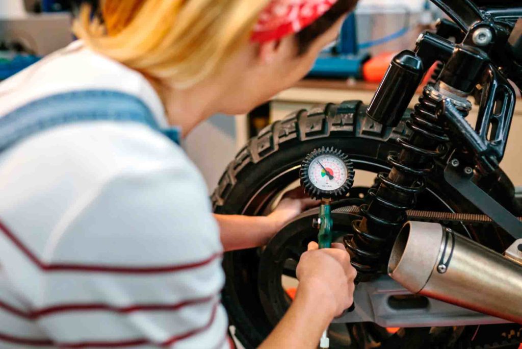 mujer en taller mecánico midiendo y ajustando la presión a los neumáticos